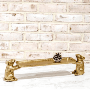 A gold colored bear bench with a brick wall in the background.